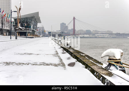 Rotterdam, The Netherlands, March 3, 2018: mooring bollards, wooden quay's edge and snow-covered cobbles at Boompjes river promenade on a cold winter  Stock Photo