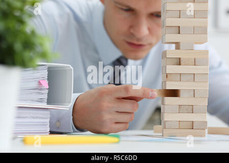 Businessman plays in a strategy of jenga hand Stock Photo