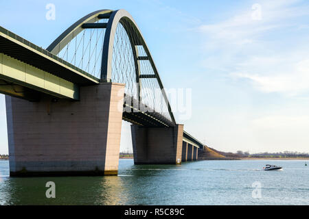 Fehmarn Sound Bridge (German: Fehmarnsundbruecke) and a fast sport boat on the Baltic Sea against a blue sky, vacation travel concept with copy space Stock Photo