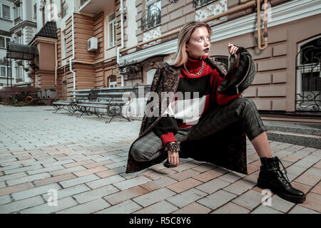 Model posing. Blonde-haired professional photo model wearing nice clothes posing outside the street Stock Photo