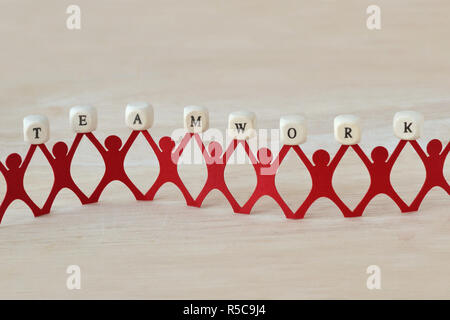 Paper people chain holding Teamwork text written on wooden cubes Stock Photo