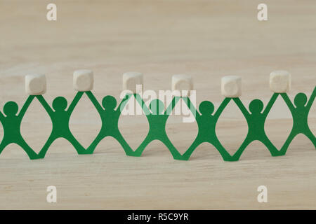 Paper people chain holding blank wooden cubes Stock Photo