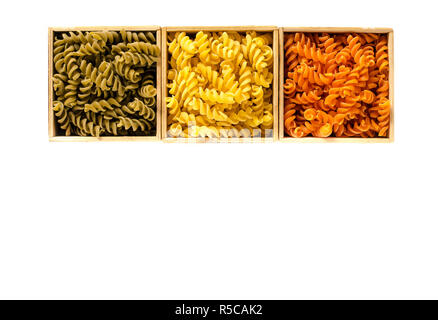 Three wooden boxes with colored fusilli are on a white background. isolated Stock Photo