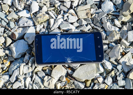 Frustrated phone on the rocks. Glass shattered on rocks on a sma Stock Photo