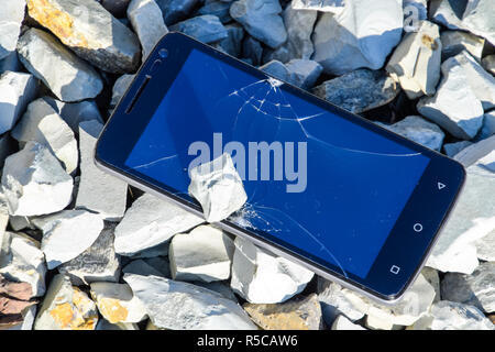 Frustrated phone on the rocks. Glass shattered on rocks on a sma Stock Photo