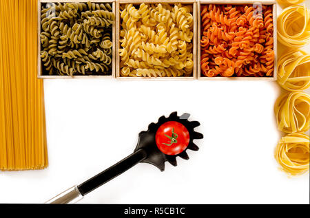 Three wooden boxes with colored fusilli are on a white background next to spaghetti and tagliatelle. isolated Stock Photo