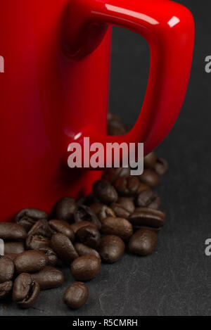 Coffee beans surrounding a red mug on a slate background with shallow depth of field. Love coffee concept Stock Photo