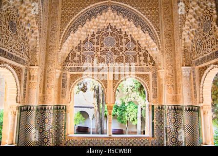 Moorish architecture in the Nasrid Palaces of the Alhambra of Granada in Spain, with beautiful intricate carvings and windows ovrlooking a garden. Stock Photo