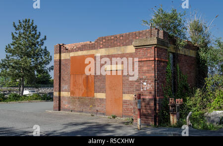 An abandoned and boarded up brick gate house near a factory Stock Photo