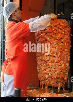 Man preparing chicken meat on a rotary spit for making Kebabs. Beyoglu district, Istanbul, Turkey Stock Photo