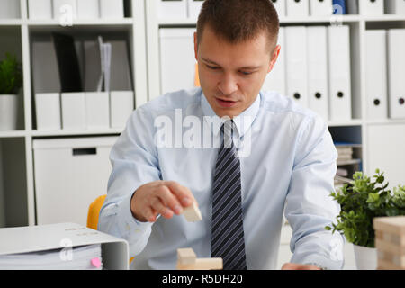 Businessman plays in a strategy of jenga hand Stock Photo