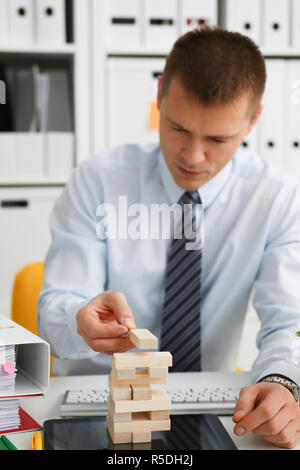 Businessman plays in a strategy of jenga hand Stock Photo