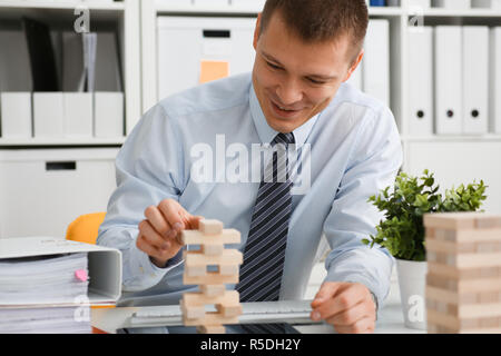 Businessman plays in a strategy of jenga hand Stock Photo