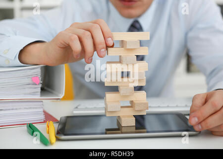 Businessman plays in a strategy of jenga hand Stock Photo