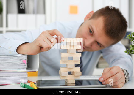 Businessman plays in a strategy of jenga hand Stock Photo