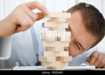 Businessman plays in a strategy of jenga hand Stock Photo