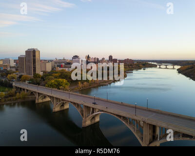 Aerial view of a bridge going over Saskatchewan River during a vibrant sunrise in the Fall Season. Taken in Saskatoon, SK, Canada. Stock Photo