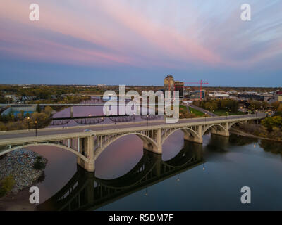 Aerial view of a bridge going over Saskatchewan River during a vibrant sunrise in the Fall Season. Taken in Saskatoon, SK, Canada. Stock Photo
