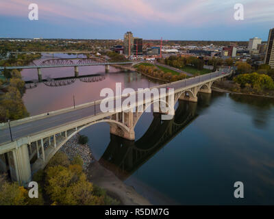 Aerial view of a bridge going over Saskatchewan River during a vibrant sunrise in the Fall Season. Taken in Saskatoon, SK, Canada. Stock Photo