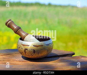 Copper Tibetan singing bowl on a brown wooden background, blurred background Stock Photo