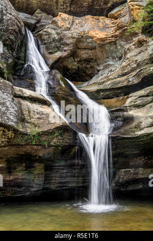 Cedar Falls, a beautiful waterfall in the Hocking Hills of Ohio, features a stream of water that splits and rejoins before plunging into a pool below. Stock Photo