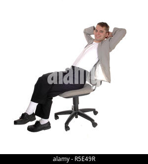 A young man in dark pants and a gray jacket sitting on a office chair with his hand behind his head, isolated for white background Stock Photo
