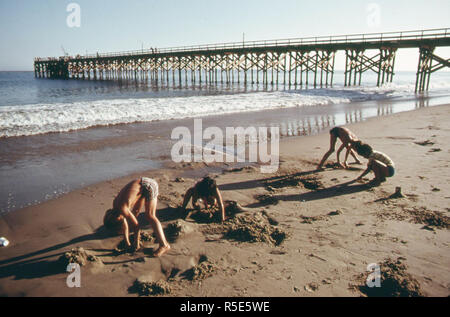 Youngsters play in the sand at the Gaviota State Beach. In the background is the pier, June 1975 Stock Photo