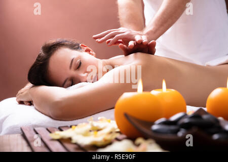 Therapist's Hand Giving Back Massage To Relaxed Young Woman In Spa Stock Photo