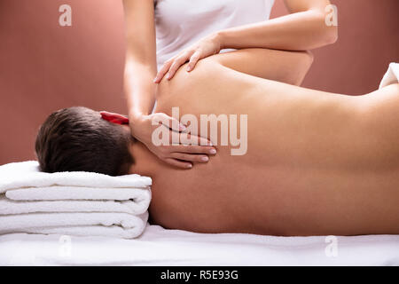 Close-up Of Therapist Hand Giving Shoulder Massage To Young Man Stock Photo
