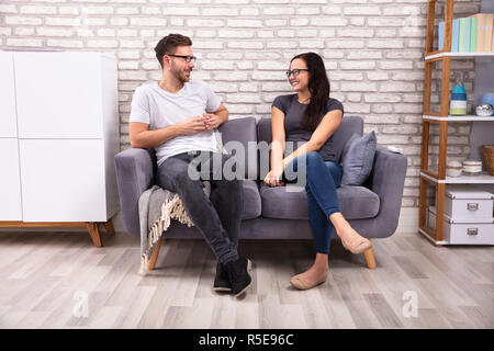 Young Men And Woman Sitting On Sofa Looking At Each Other During Date Stock Photo