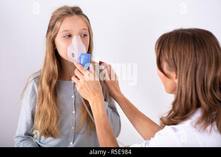 Close-up Of Female Doctor Using Inhaler Mask On Girl In Clinic Stock Photo