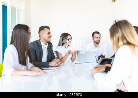 Group of diverse business executives holding a meeting around a table discussing graphs showing statistical analysis Stock Photo