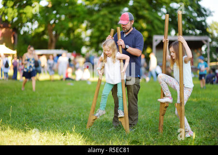 Father and children walking on stilts during annual Medieval Festival, held in Trakai Peninsular Castle. Fun activity for kids and parents. Stock Photo