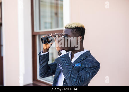 african american electrical manager using binoculars looking at substation Stock Photo