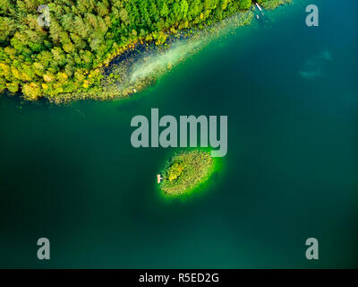 Aerial top down view of small island. Birds eye view of beautiful green waters of lake Gela surrounded by pine forests. Clouds reflecting in Gela lake Stock Photo
