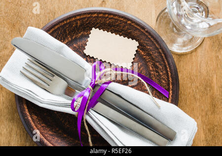 Festive Table Setting With Empty Tag. Napkin, plate and cutlery on wooden table. Holidays background. Selective Focus. Stock Photo