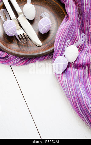 Festive table setting for Easter dinner with easter eggs. Napkin, plate and cutlery on wooden table. Holidays background. Selective Focus. Stock Photo