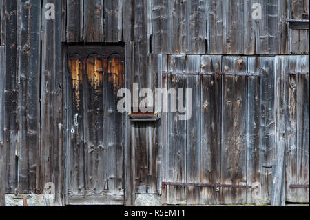 Weather worn wooden doors on wood panel building Stock Photo