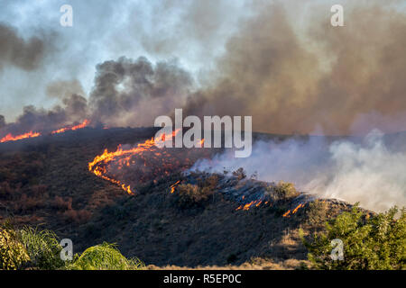 Wildfire flames burn hillside brush with dramatic shapes and color in California's Woolsey Fire. Stock Photo