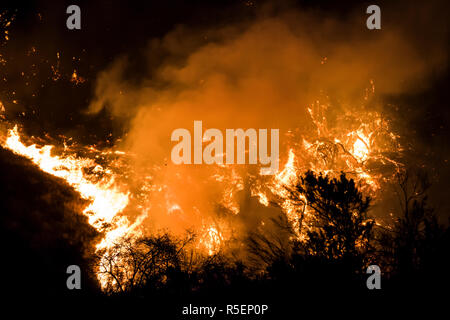 Wildfire flames burn hillside brush at night with dramatic shapes and color in California's Woolsey Fire Stock Photo