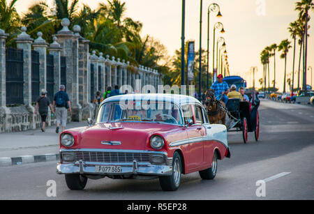 Classic cars, tourists and horse drawn carriages on the Malecon at sunset. Stock Photo