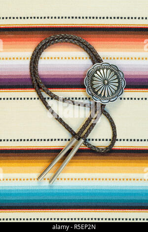 Vintage Sterling Silver Bolo Tie with Concho and Silver Tips on colorful southwestern hand woven fabric. Stock Photo