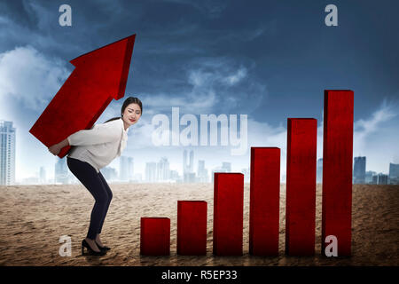 Asian business woman lifting heavy arrow Stock Photo