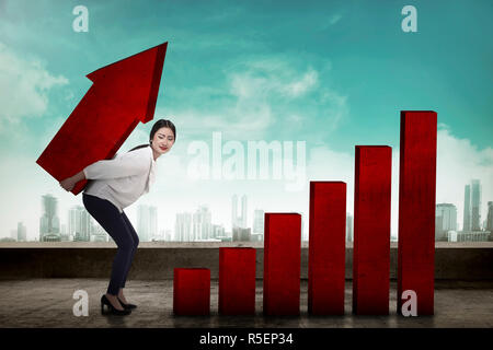 Asian business woman lifting heavy arrow Stock Photo