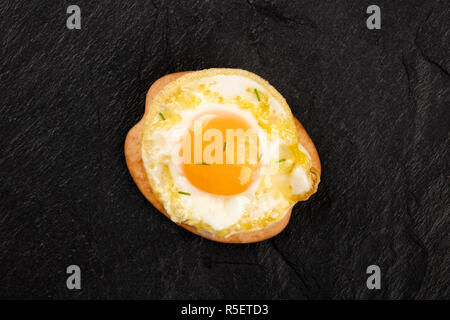 A photo of a quail egg, shot from the top, on a cracker, on a black background with copy space Stock Photo