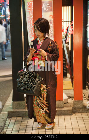 Japan, Tokyo, Roppongi, Young Girl in Kimono Holding Two Mobile Phones