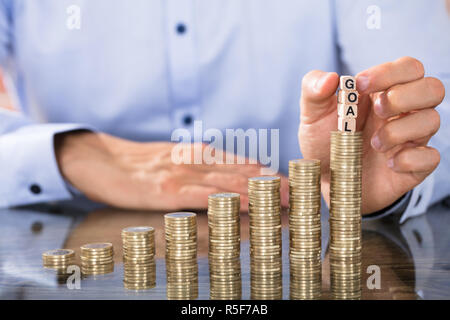 Hand Holding Goal Blocks Over The Coin Stack Stock Photo