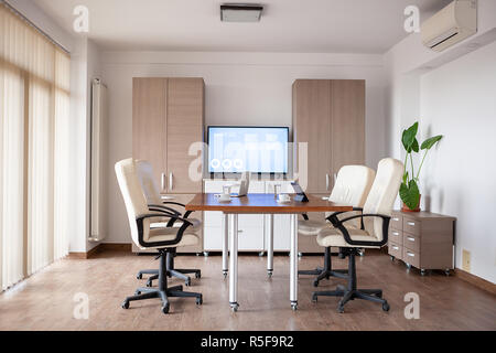 Empty conference room in business center. There is a TV displaying some graphs and charts on the background Stock Photo