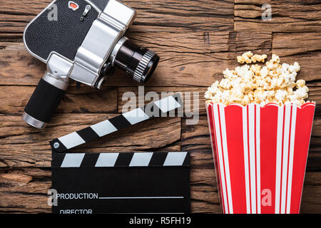 Movie Camera With Clapper Board And Popcorn On Wood Stock Photo