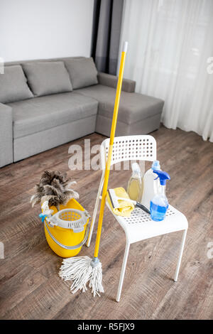 Bucket with dust wiper, sponges, chemicals bottles and mopping stick on the floor in the apartment. Cleaning service concept Stock Photo